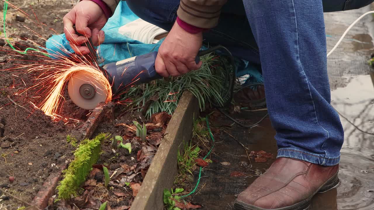 Male hands are cutting rusty metalwork with a grinder