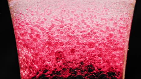 macro shot of sparkling red bubbles floating around in a glass with bright background