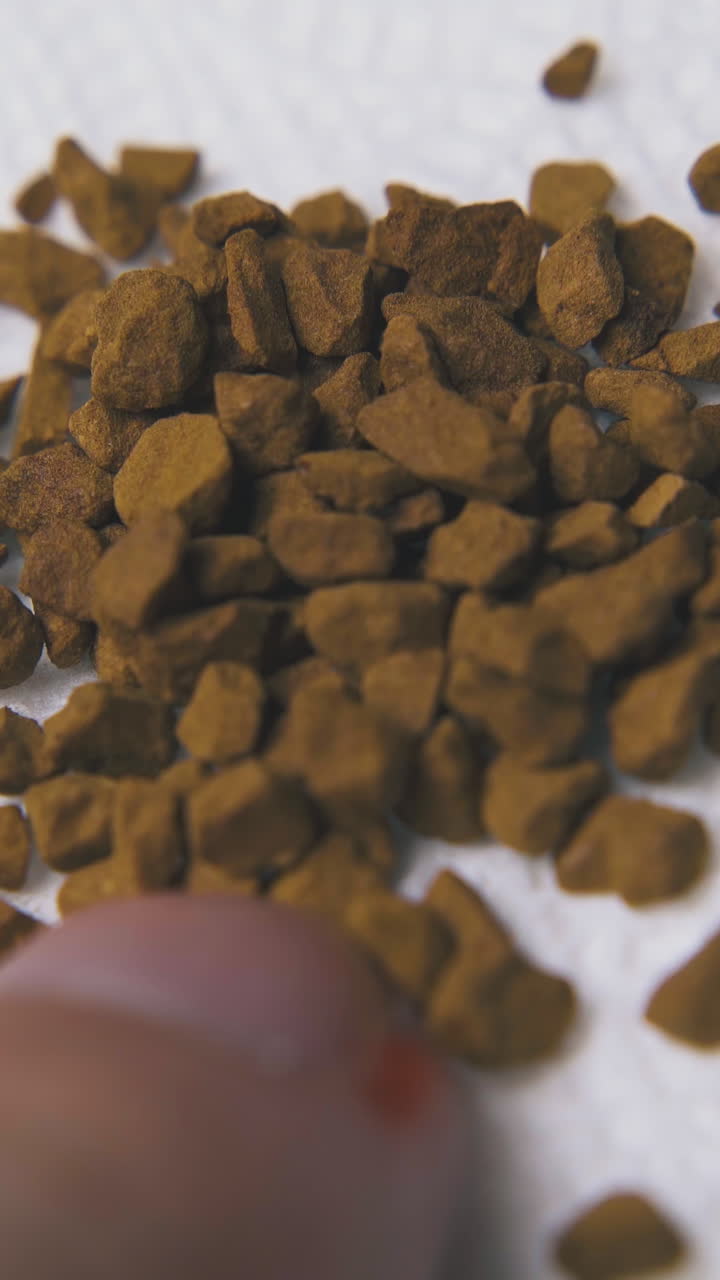 young person pours brown instant coffee granules onto white paper napkin extreme close view