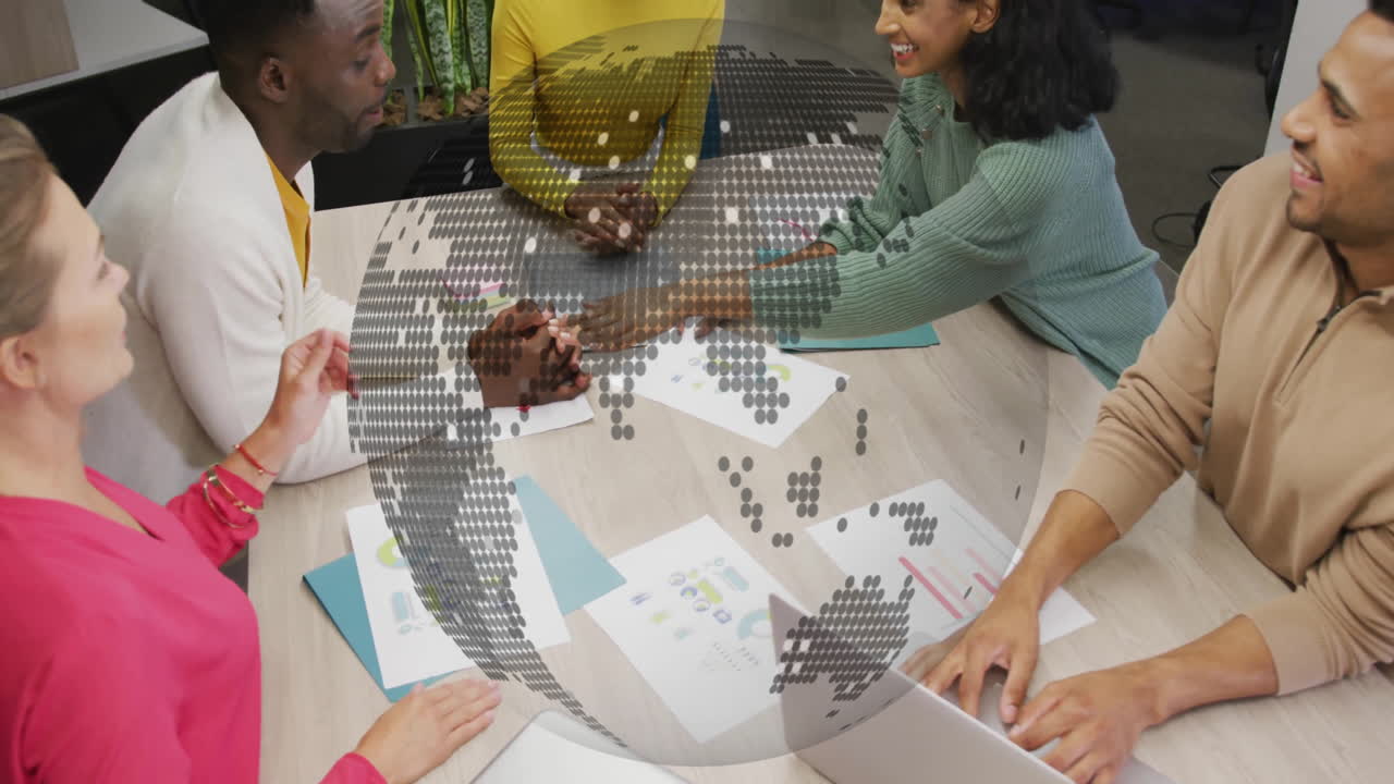 Diverse team collaborating at table with digital globe animation overlay