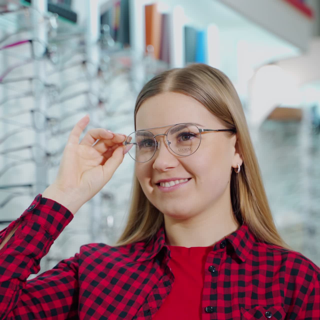 Smiling woman wearing new stylish glasses. Beautiful girl buying eyeglasses in the optical store. Female customer choosing spectacles.