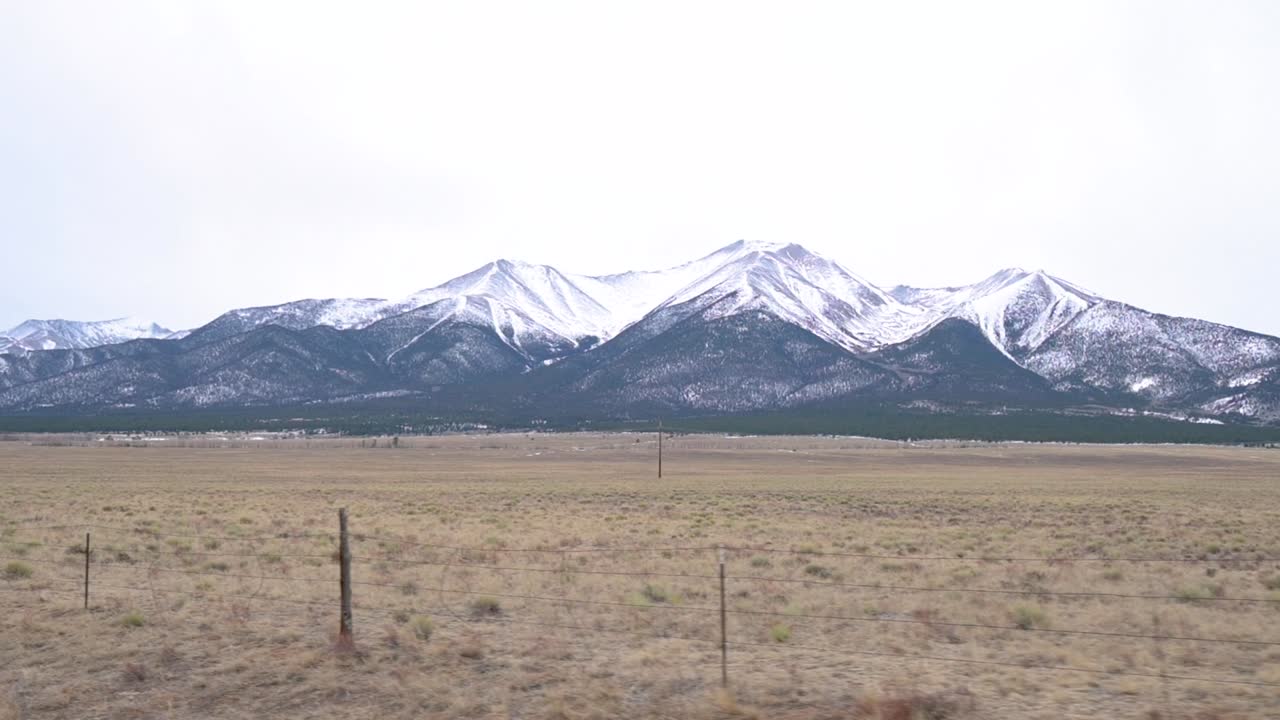 Driving past the snow-capped Collegiate Peaks on an overcast day in Colorado during the winter