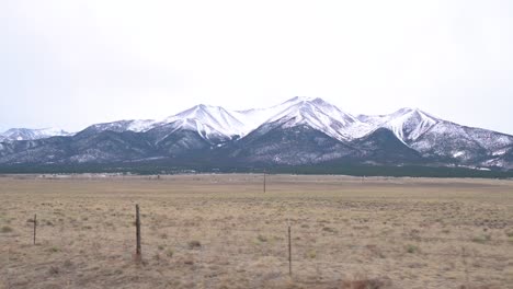 driving past the snow-capped collegiate peaks on an overcast day in colorado during the winter