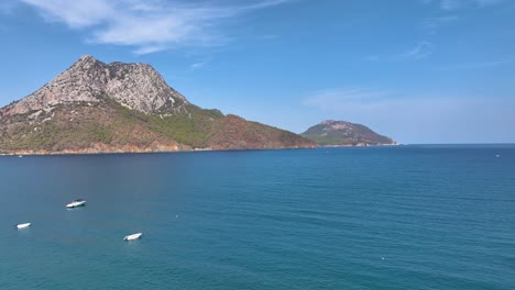 paisaje costero con barcos y montañas