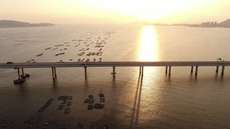 Traffic-on-Hong-Kong-Shenzhen-Bay-Bridge-at-Sunset,-with-Fish-and-Oyster-cultivation-pools,-Aerial-view