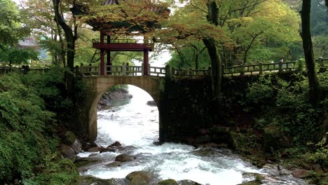 mountain stream flows through arch of korean foot bridge