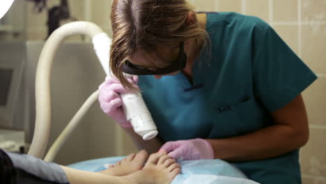 Doctor-Haciendo-Un-Tratamiento-Con-Láser-En-Los-Pies-Y-Las-Uñas-De-Una-Mujer.