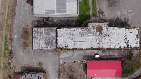 top down drone footage moving left over a large abandoned brick building with a decaying roof