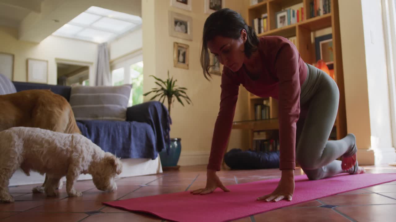 mujer caucásica practicando yoga con sus perros domésticos en casa