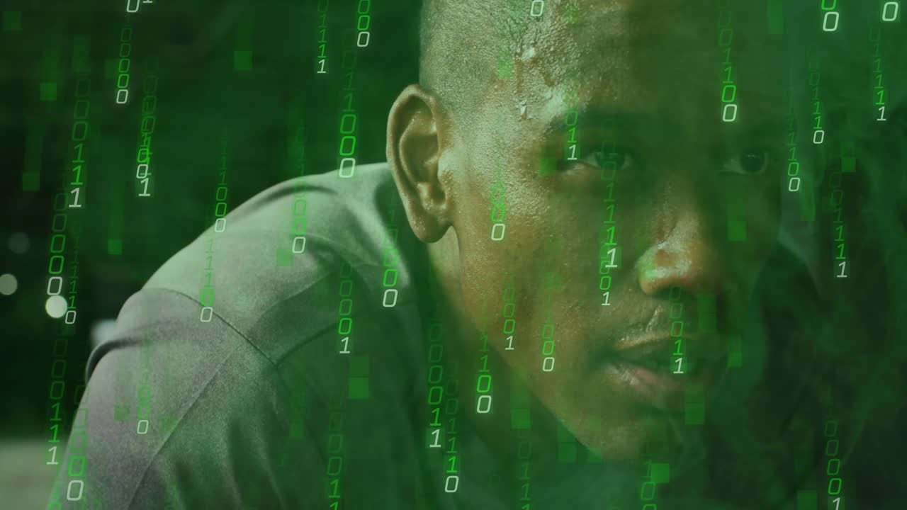 Binary code overlaying man's face, concentrating on digital work in office setting