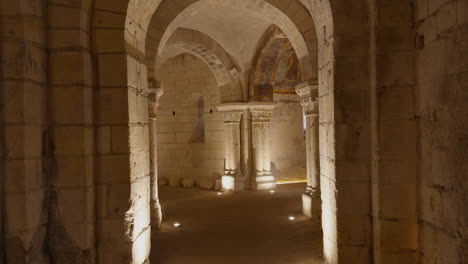 ancient crypt with romanesque arches, medieval frescoes, and dim atmospheric lighting