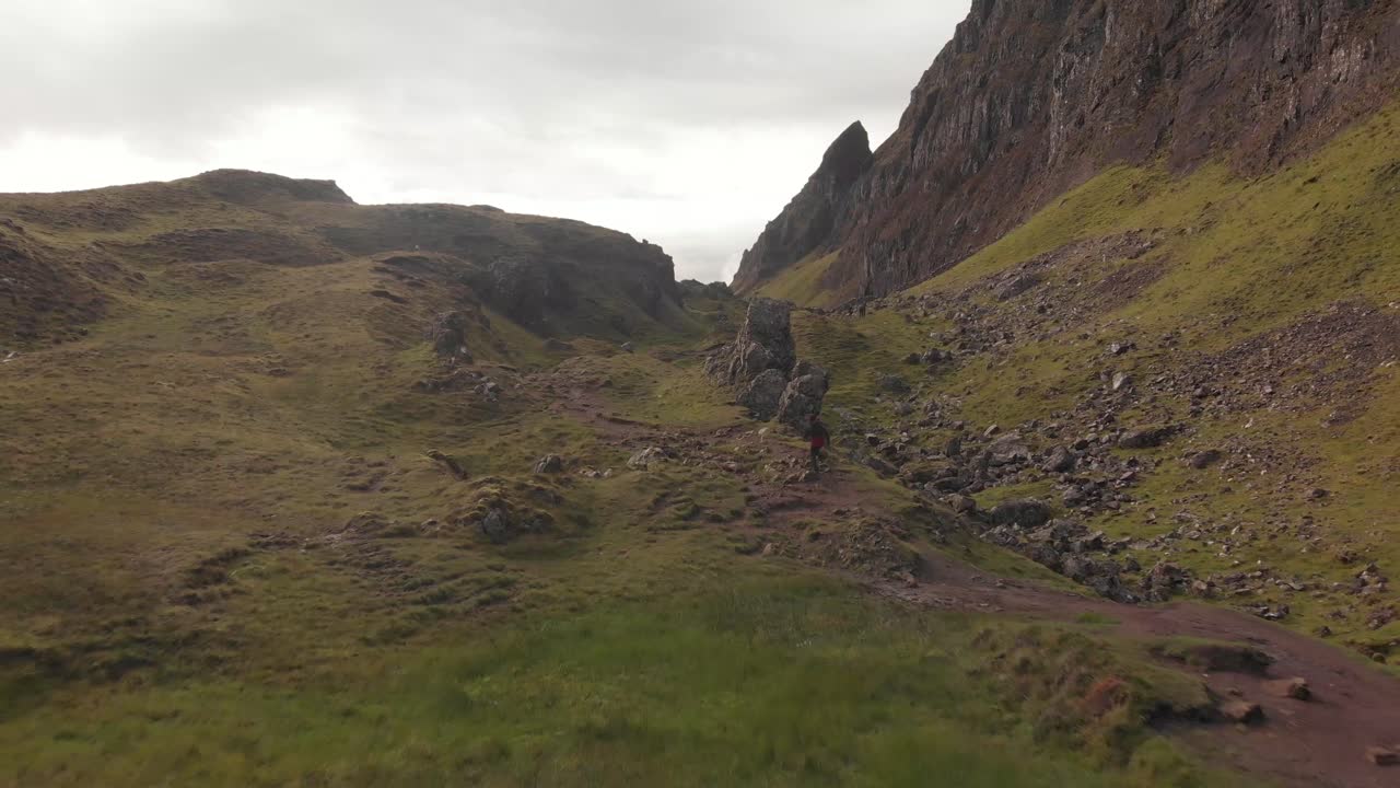 joven corriendo y haciendo senderismo en el paisaje de hierba verde quiraing en las montañas de la isla de skye escocia