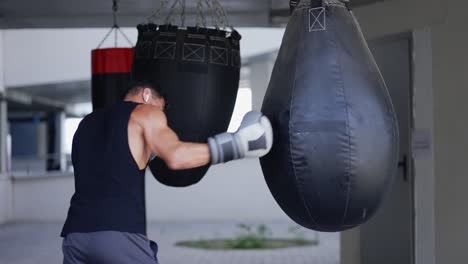The-man-executes-strong-blows-in-the-boxing-bag,-outdoors
