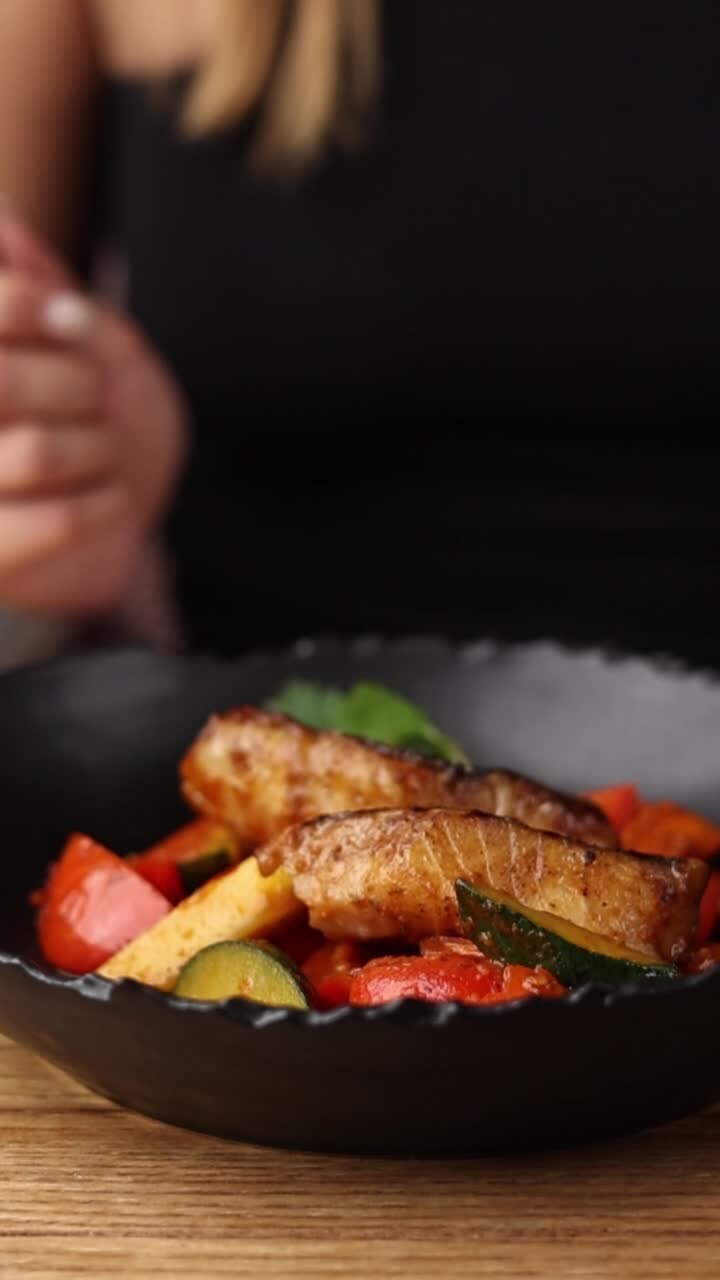 Mujer comiendo pescado con verduras
