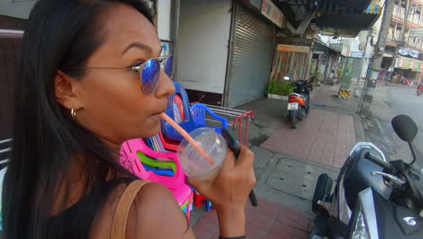 slow motion | indian woman walking down the street in asia drinking from a straw