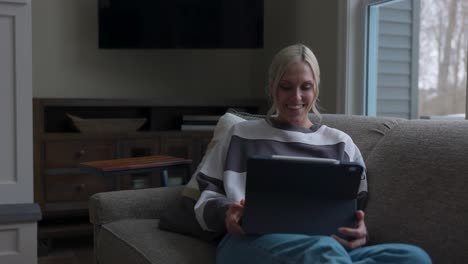 woman-walking-to-the-couch-to-lay-down-and-scroll-through-tablet-while-drinking-coffee-in-a-nice-house