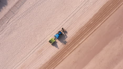 Fallende-Kamerafahrt-Eines-Traktoranhängers,-Der-Einen-Sandstrand-In-Nord-Devon-Reinigt