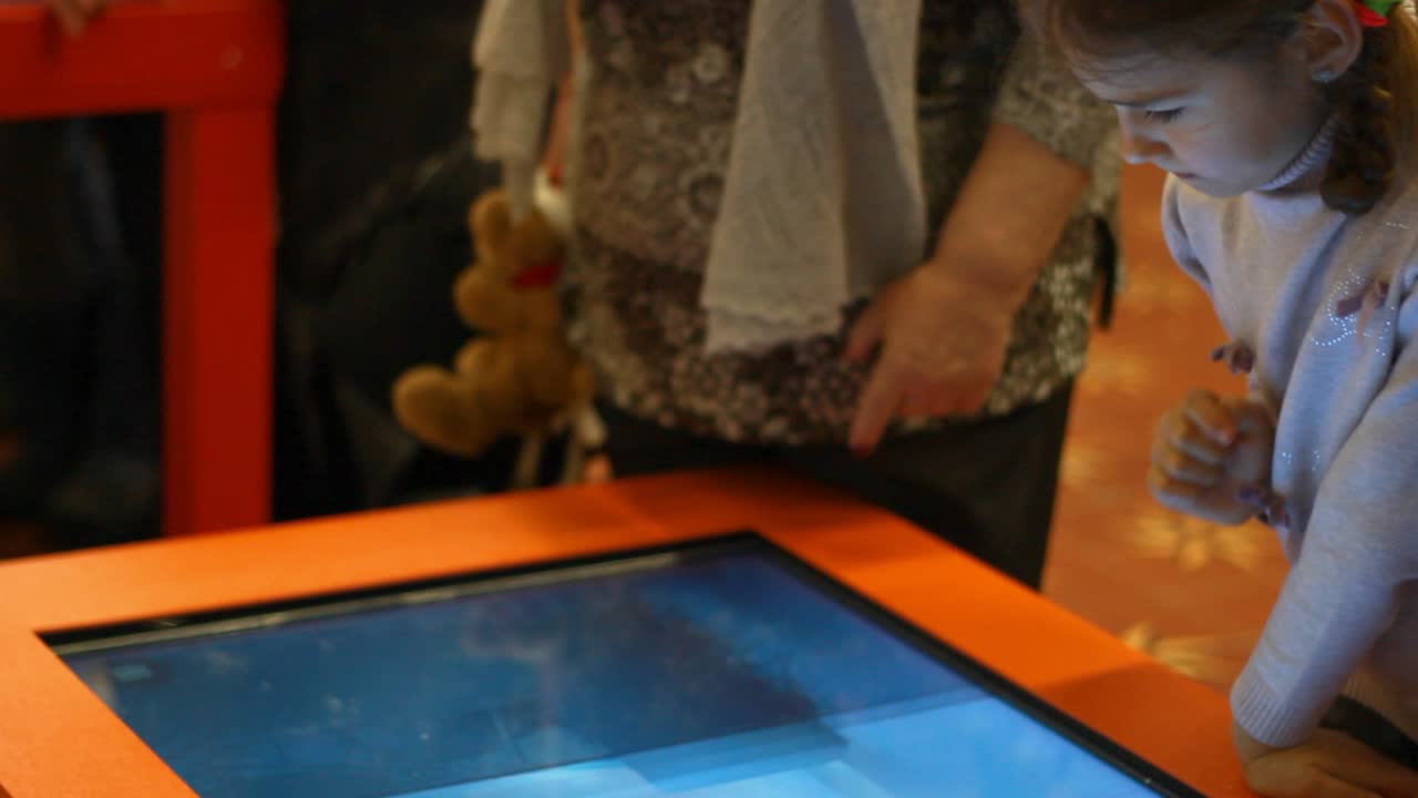 비디오 게임을 하는 소녀. 터치 스크린 게임을 하는 소녀 아이. 인터랙티브 게임