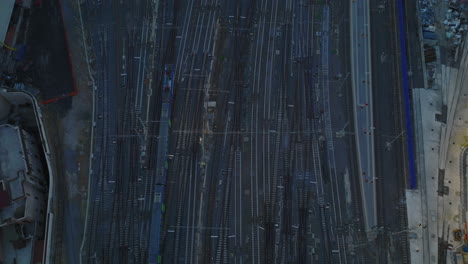 High-angle-view-of-train-driving-on-railroad-tracks.-Tilt-up-reveal-building-on-central-train-station-and-city-at-dusk.-Rome,-Italy