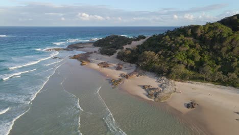 lush green trees at deadmans headland reserve park along sandy beach with waves - point lookout, north stradbroke island, qld, australia