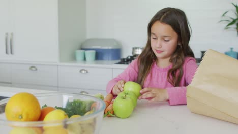 chica caucásica feliz desempaquetando comestibles en la cocina