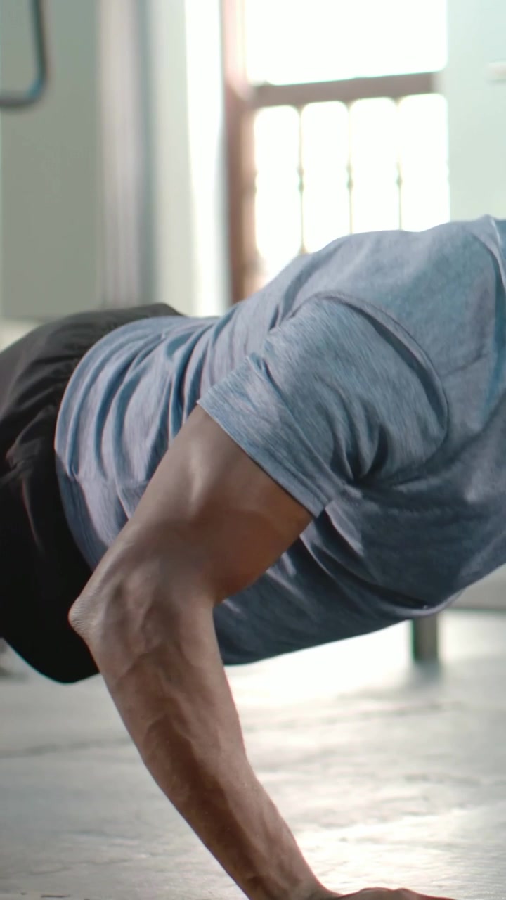 Vertical video: Starting plank, man grey tee doing pushups at gym training, with blue balls