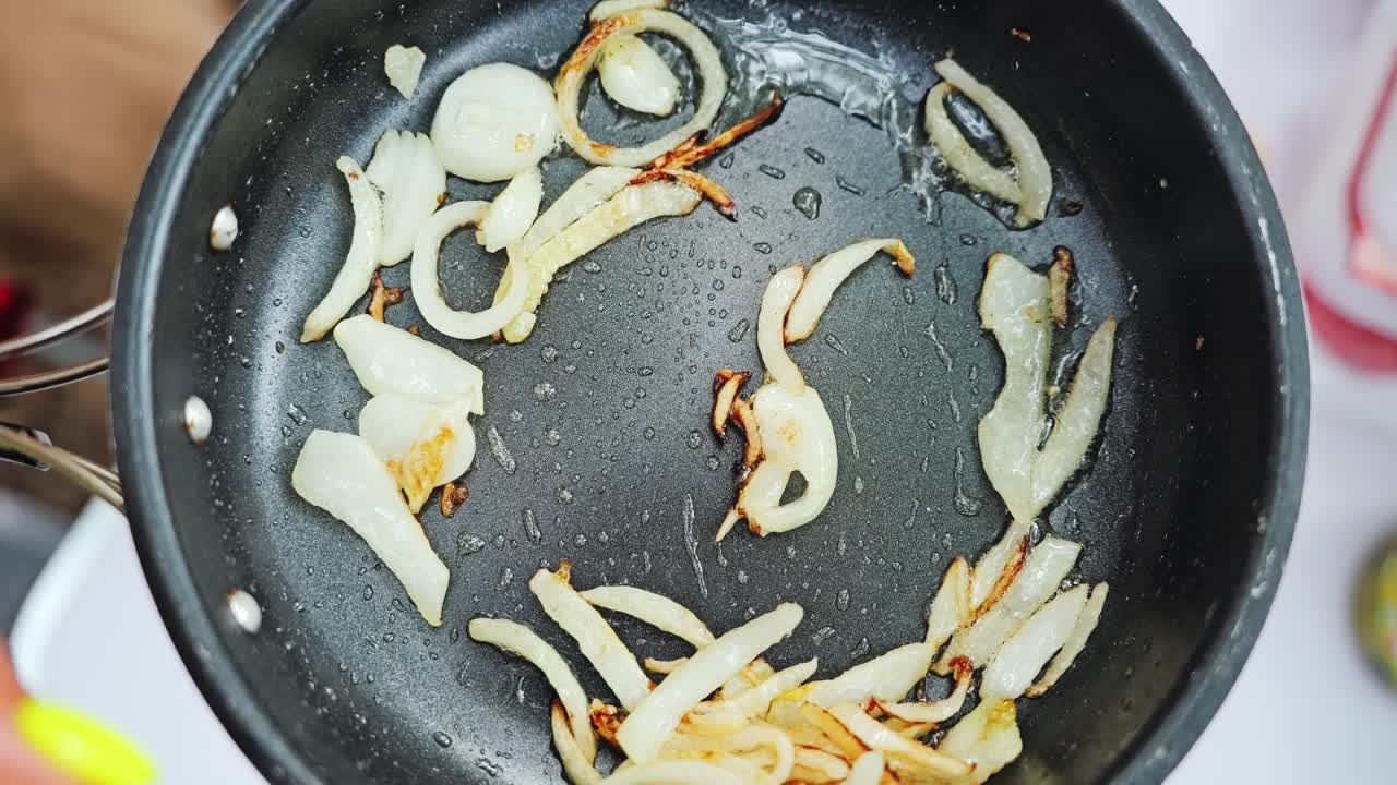 Outdoor cooking moment with sizzling onions in frying pan during slow motion