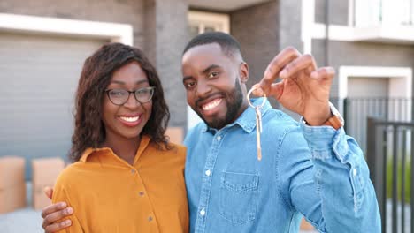 Portrait-of-happy-cheerful-young-African-American-couple-smiling-to-camera-and-showing-to-camera-keys-of-new-home