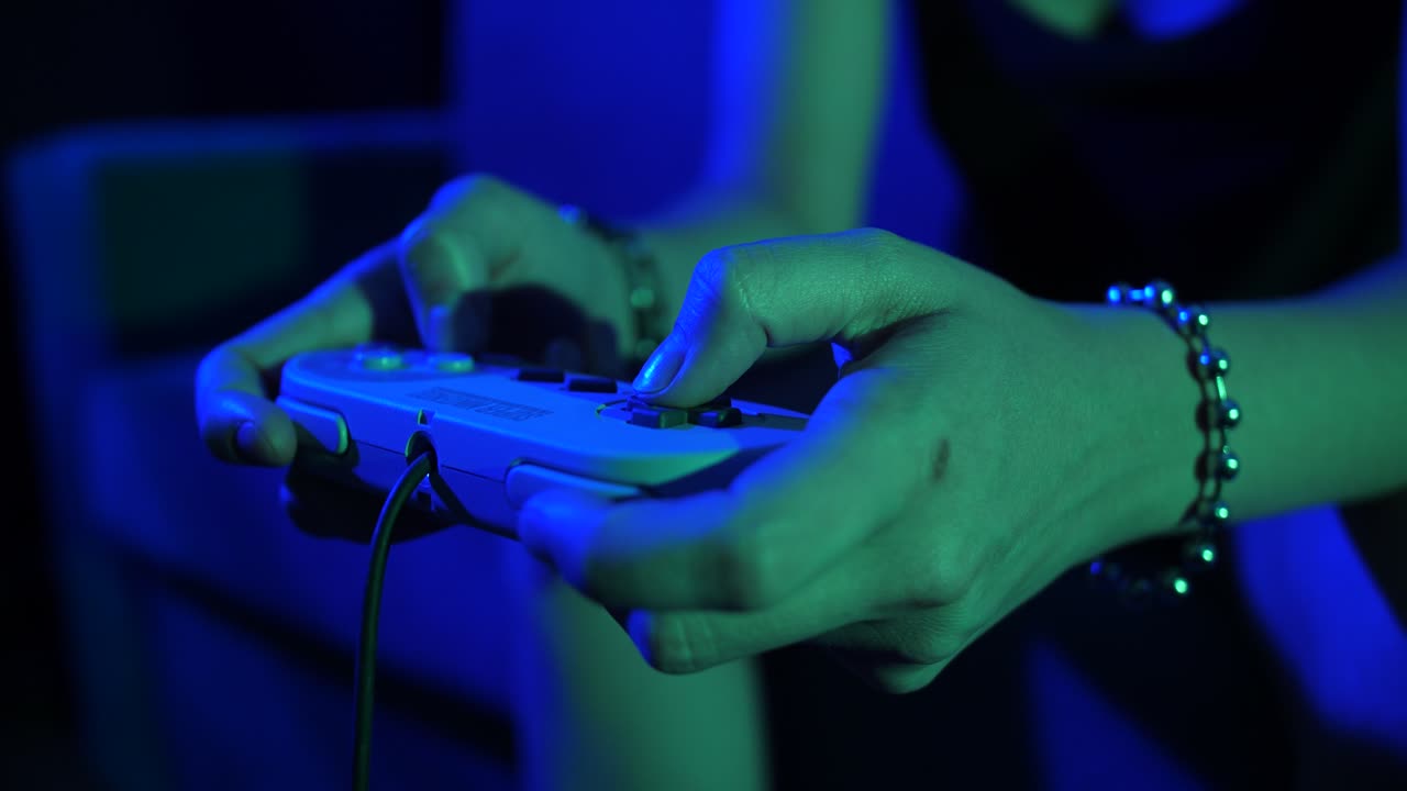 Close-up of Hands Playing Retro Video Game with Controller in Neon Light