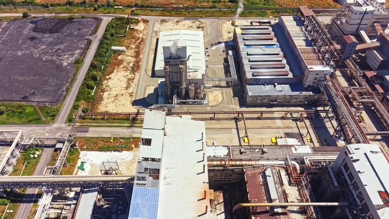 Complesso industriale e fabbrica in un'area di produzione che mostra edifici, tubazioni e macchinari, ritraendo una giornata di intensa attività.