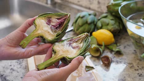 mujer limpiando alcachofas. proceso de cocción en la cocina. primer plano