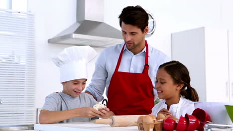 father watching son stretch pastry with sister