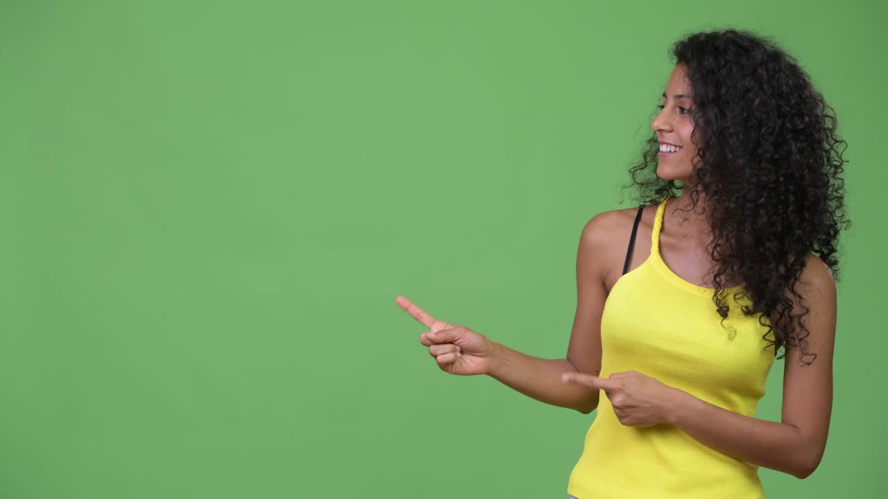 Young beautiful Hispanic woman showing something