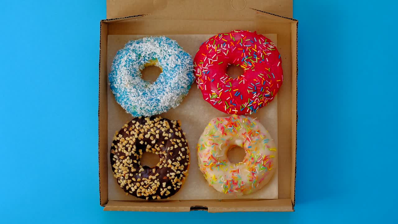 manos femeninas abren caja con rosquillas en fondo amarillo