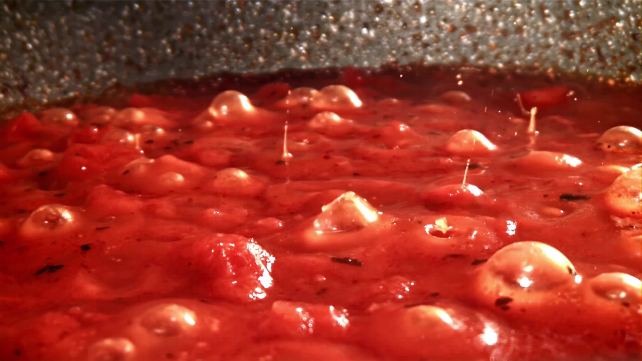 Salsa di pomodoro rosso vivace che sobbolle con bollicine in una padella calda.