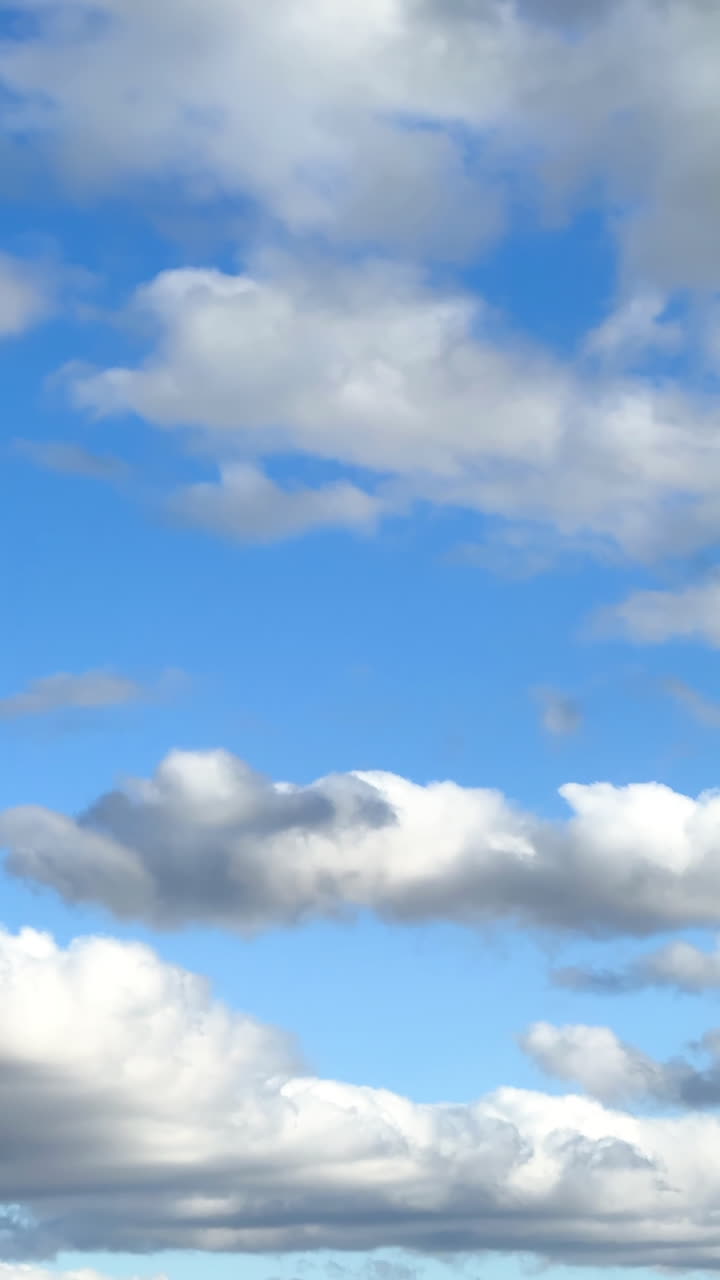 Mesmerizing view of the clouds floating by the blue sky. Light and heavy grey clouds in the atmosphere. Vertical video.