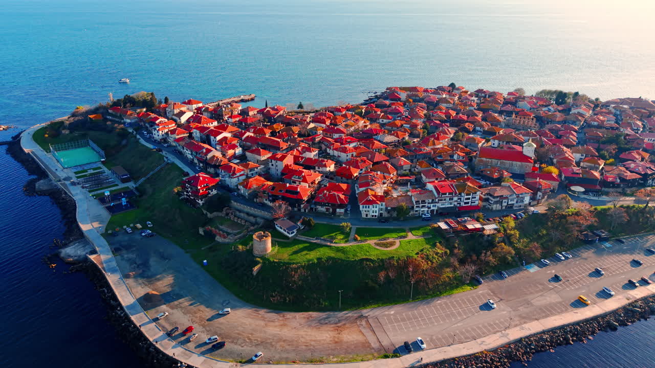 Droneperspektiv af en kystbys udkant med parkeringsplads, park og traditionelle bygninger ved havet. Luftfoto af kystlinjen med huse med røde tage i Bulgarien.