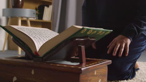 close up of muslim woman at home kneeling and reciting from the quran 2