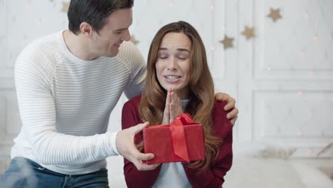 mujer bonita esperando regalo con los ojos cerrados en la sala de estar.