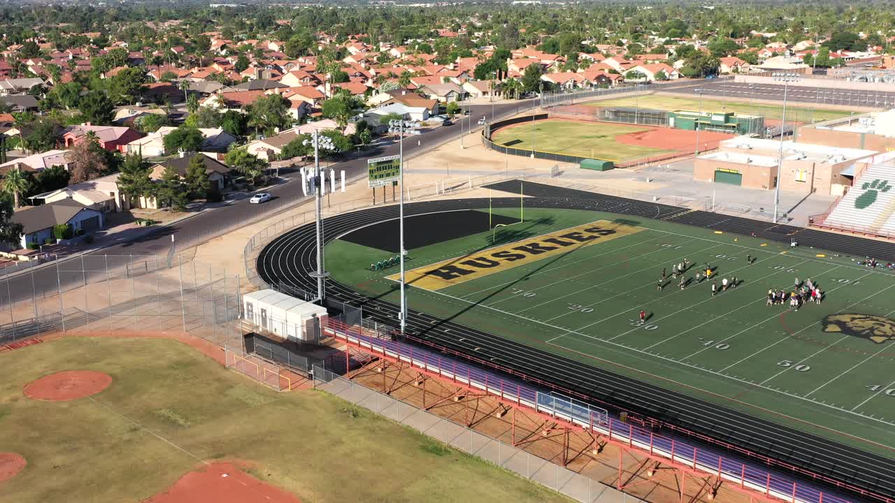 Aerial pull back from a football field where spring practice is taking place.