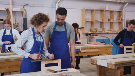 Nachhilfelehrer-Mit-Tischlerstudent-In-Der-Werkstatt,-Der-Für-Eine-Ausbildung-An-Der-Hochschule-Mit-Holzhobel-Studiert