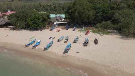 aerial orbits blue fishing boats pulled onto kantiang beach, thailand