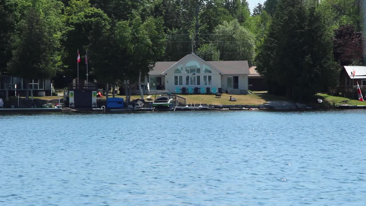 Casas à beira-mar e porto cercados por árvores verdes perto dos lagos Kawartha, em Ontário, Canadá, em um dia ensolarado. - plano aberto