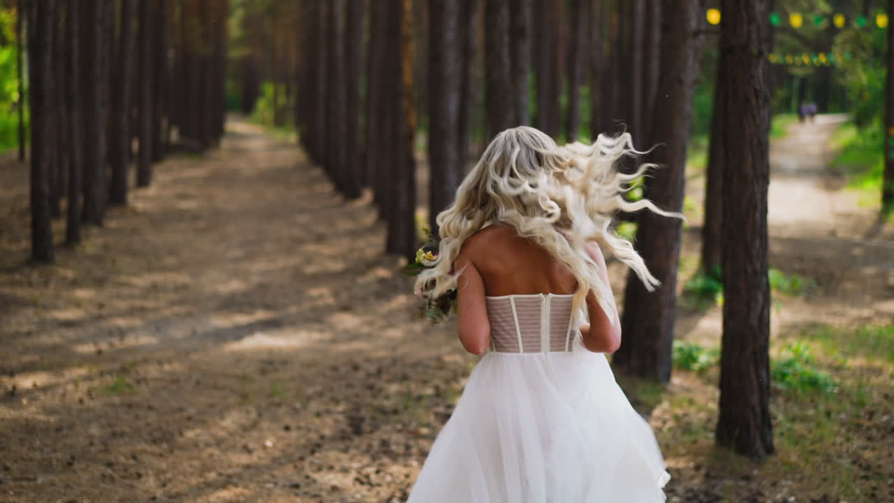 Bella donna in elegante abito da sposa corre lungo il parco.