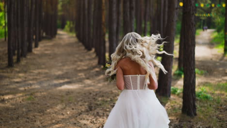 Pretty-woman-in-elegant-wedding-dress-runs-along-park