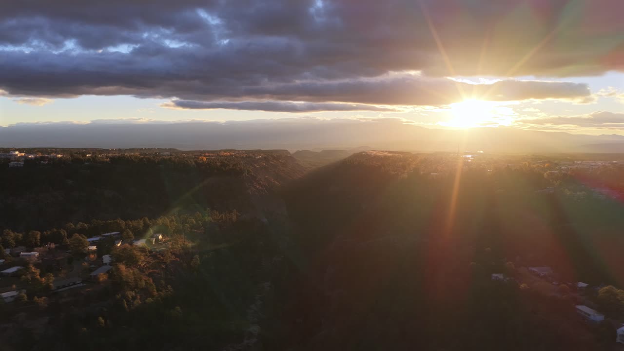 Drone glides sideways while orbiting a mountain canyon at sunrise, capturing warm golden light, dramatic clouds, and sweeping forest landscape in a smooth cinematic aerial shot
