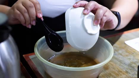 person transfers soup from small to large bowl