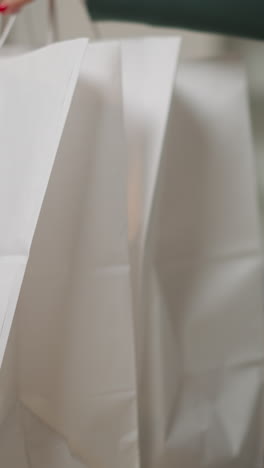 hungry boy waits for dinner sitting at table feeling bored and playing with popcorn. mother enters kitchen carrying bags of food on blurred background closeup