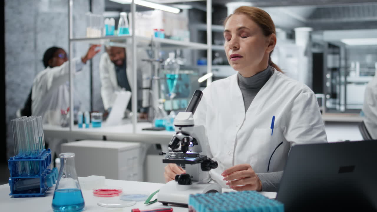 Histology technician using microscope fixing bad posture at workbench