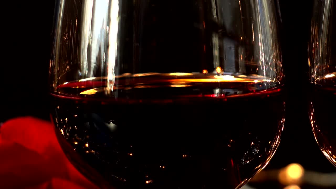 Bicchieri da vino e rosa sullo sfondo di ghirlande luminose.